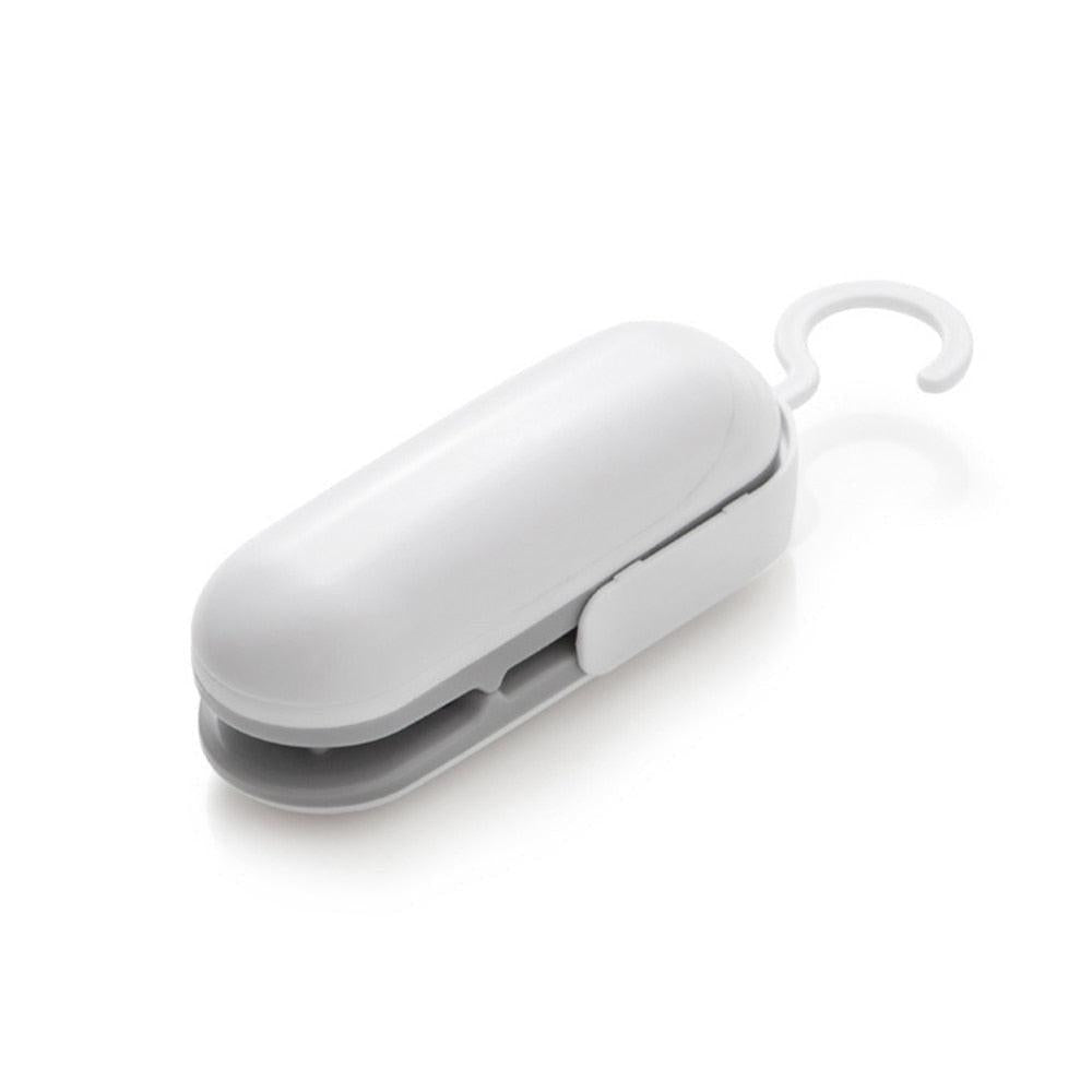 Portable Dev2-Aff mini heat bag sealing machine with white plastic sealer bags for food and kitchen packaging.