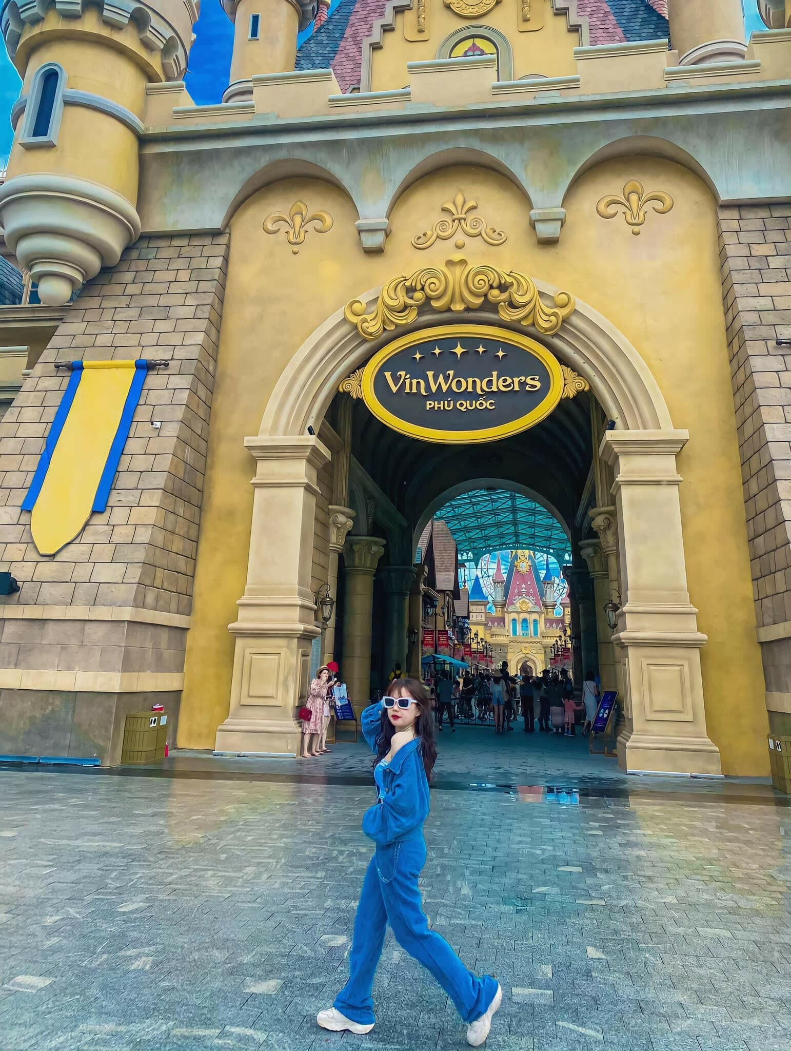 Entrance archway of VinWonders Phu Quoc amusement park with a woman walking in front wearing blue outfit
